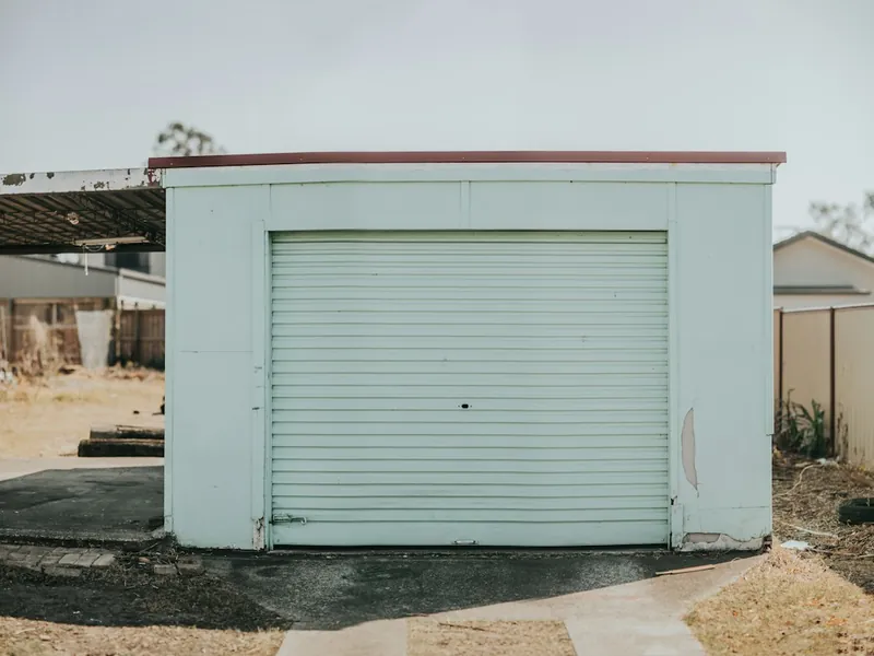 Detached garage with a roll-up door that needs off-track repair